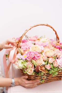 Kadın el hasır sepet pembe tablo renklerde çeşitli çiçek aranjmanı dokun. güzel bahar buket. parlak oda, beyaz duvar. kopya alanı