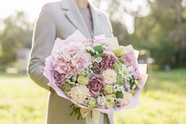 Young girl holding a beautiful spring bouquet. flower arrangement with hydrangea and garden roses. Color light pink. Bright dawn or sunset sun — Stock Photo, Image