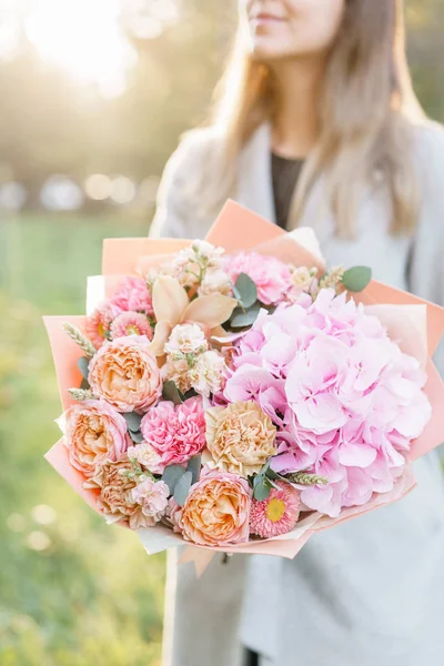 Buchet frumos de primăvară. Fata tânără care deține un aranjament de flori cu diferite culori. Zori strălucitori sau apus de soare — Fotografie, imagine de stoc