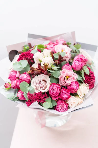 Красивый весенний букет. цветы расположение с различными цветами в стеклянной вазе на розовом столе. светлая комната, белая стена — стоковое фото