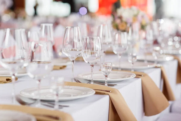 Mesa en una recepción de boda de lujo. Hermosas flores en la mesa. Sirve platos, vasos de vidrio, camareros trabajan , — Foto de Stock