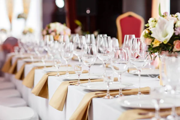 Mesa en una recepción de boda de lujo. Hermosas flores en la mesa. Sirve platos, vasos de vidrio, camareros trabajan , — Foto de Stock