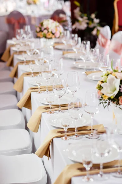 Mesa en una recepción de boda de lujo. Hermosas flores en la mesa. Sirve platos, vasos de vidrio, camareros trabajan , — Foto de Stock