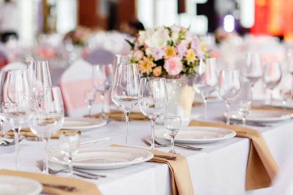 Mesa en una recepción de boda de lujo. Hermosas flores en la mesa. Sirve platos, vasos de vidrio, camareros trabajan , — Foto de Stock