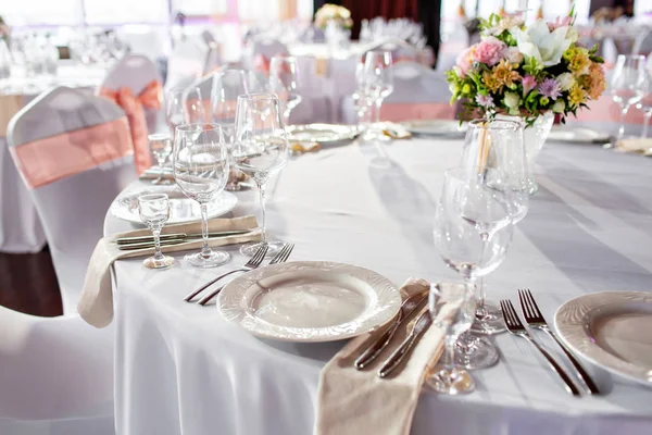 Kerek asztal egy luxus esküvői fogadás. Gyönyörű virágok az asztalra. Ételeket szolgálnak fel, üveg szemüveg, pincérek munka, — Stock Fotó