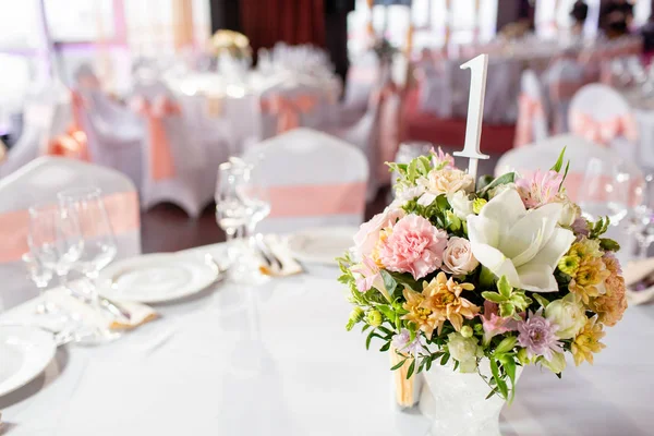 Mesa redonda en una recepción de boda de lujo. Hermosas flores en la mesa. Sirve platos, vasos de vidrio, camareros trabajan , — Foto de Stock