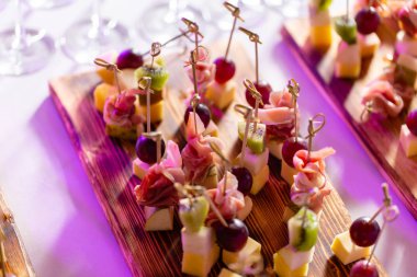 Resepsiyon büfedeki. Kanepeler ahşap tahta üzerinde ürün yelpazesine. Ziyafet Servisi. Gıda catering, peynir, jamon, prosciutto ve meyve ile aperatifler