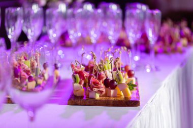 Resepsiyon büfedeki. Bardak şarap ve şampanya. Kanepeler ahşap tahta üzerinde ürün yelpazesine. Ziyafet Servisi. Gıda catering, peynir, jamon, prosciutto ve meyve ile aperatifler