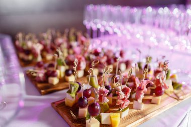 Resepsiyon büfedeki. Bardak şarap ve şampanya. Kanepeler ahşap tahta üzerinde ürün yelpazesine. Ziyafet Servisi. Gıda catering, peynir, jamon, prosciutto ve meyve ile aperatifler