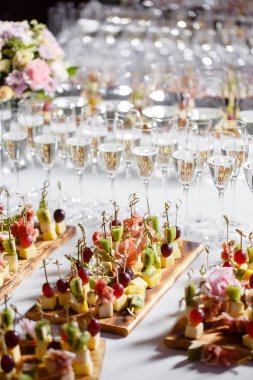 Resepsiyon büfedeki. Bardak şarap ve şampanya. Kanepeler ahşap tahta üzerinde ürün yelpazesine. Ziyafet Servisi. Gıda catering, peynir, jamon, prosciutto ve meyve ile aperatifler