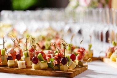 Resepsiyon büfedeki. Bardak şarap ve şampanya. Kanepeler ahşap tahta üzerinde ürün yelpazesine. Ziyafet Servisi. Gıda catering, peynir, jamon, prosciutto ve meyve ile aperatifler