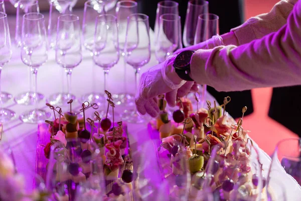 Garson hazırlanan ve bir aperatif hizmet vermektedir. Resepsiyon büfedeki. Kanepeler ahşap tahta üzerinde ürün yelpazesine. Ziyafet Servisi. Gıda catering, peynir, jamon, prosciutto ve meyve ile aperatifler