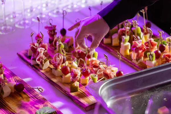 Garson hazırlanan ve bir aperatif hizmet vermektedir. Resepsiyon büfedeki. Kanepeler ahşap tahta üzerinde ürün yelpazesine. Ziyafet Servisi. Gıda catering, peynir, jamon, prosciutto ve meyve ile aperatifler
