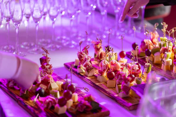 The buffet at the reception. Glasses of wine and champagne. Assortment of canapes on wooden board. Banquet service. catering food, snacks with cheese, jamon, prosciutto and fruit — Stock Photo, Image
