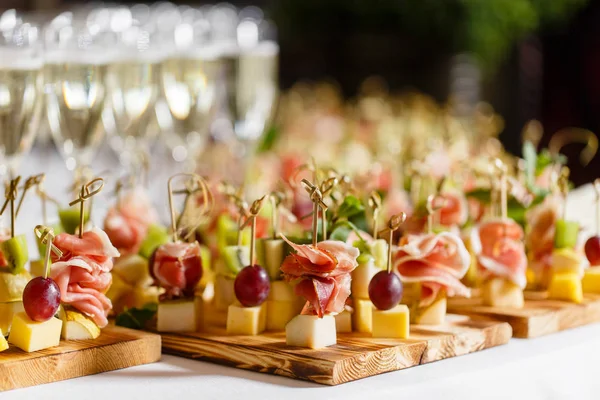 O buffet na recepção. Copos de vinho e champanhe. Sortimento de canapés no tabuleiro de madeira. Serviço de banquetes. comida de catering, lanches com queijo, jamon, prosciutto e frutas — Fotografia de Stock