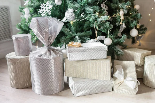 Ajándékok és ajándékdobozok a karácsonyfa alatt. Bézs dobozok szalagmasnival. Szilveszterkor díszített belső tér. Téli nyaralás koncepciója. — Stock Fotó