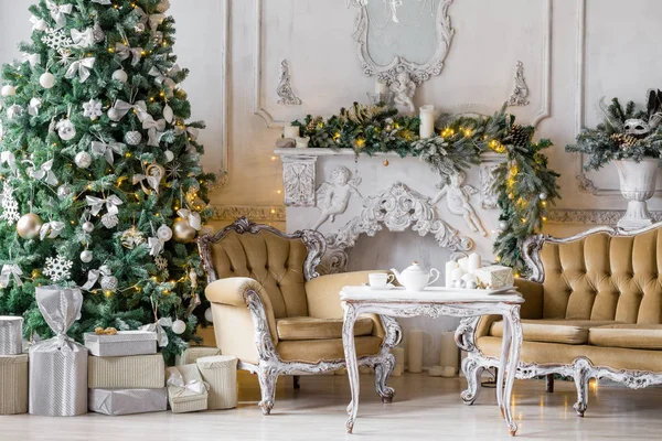 Weihnachtsmorgen. klassische Appartements mit weißem Kamin, geschmücktem Tannenbaum, Sofa, großen Fenstern und Kronleuchter. — Stockfoto