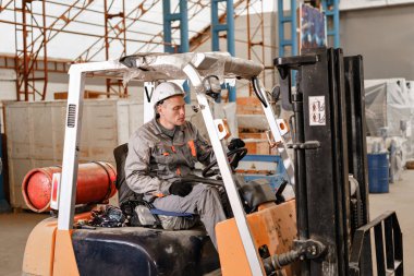 adam bir fabrikada bir ambar yoluyla forklift sürüş. sürücü düzgün ve koruyucu kask içinde. Lojistik ve depolama kavramı