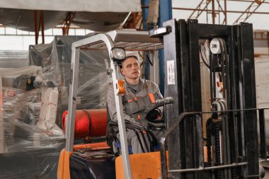 adam bir fabrikada bir ambar yoluyla forklift sürüş. sürücü düzgün ve koruyucu kask içinde. Lojistik ve depolama kavramı