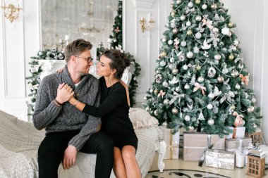 Genç bir çift. Mutlu bir aile evde eğleniyor. Noel sabahı parlak oturma odasında. Yeni Yılınız Kutlu Olsun. süslü Noel ağacı