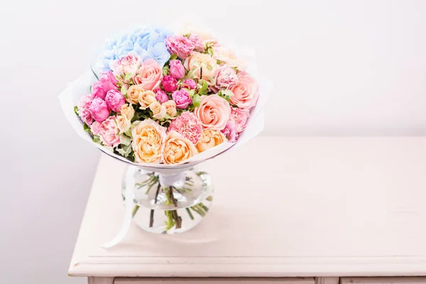 Hermoso ramo de primavera. arreglo de flores con varios colores en jarrón de vidrio sobre mesa rosa. habitación luminosa, pared blanca. espacio de copia —  Fotos de Stock