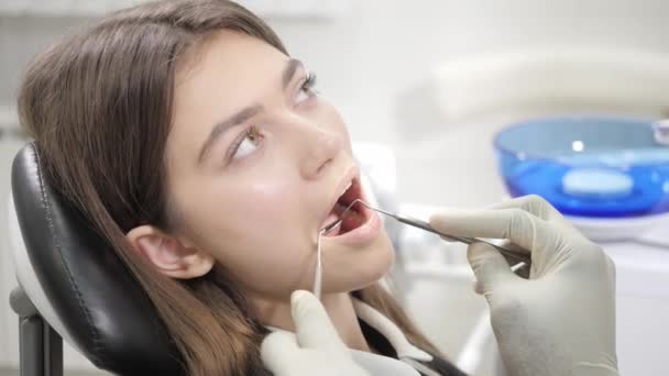 Retrato de una joven hermosa en la silla del dentista en la clínica dental. Medicina, salud, concepto estomatológico. dentista tratando a un paciente. Mujer sonriendo — Vídeos de Stock