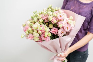 güzel bahar buket. Bir çiçek düzenleme lisianthus ile pembe renk tutan genç kız. beyaz duvar.