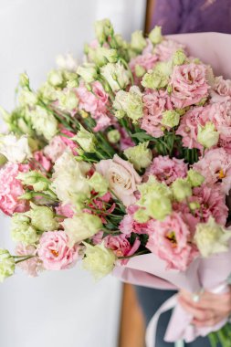 güzel bahar buket. Bir çiçek düzenleme lisianthus ile pembe renk tutan genç kız. beyaz duvar.