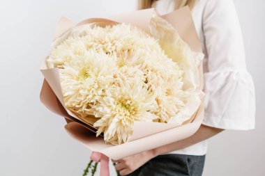 nadir krizantem yemyeşil buket. Bir çiçek düzenlemeleri çeşitli renklerin tutan genç kız. beyaz duvar.