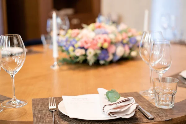 Konzentrieren sich auf die Serviette mit Eukalyptus. schöner Blumenschmuck. Hochzeitsbankett oder Galadinner. Stühle und Tisch für die Gäste, serviert mit Besteck und Geschirr. — Stockfoto