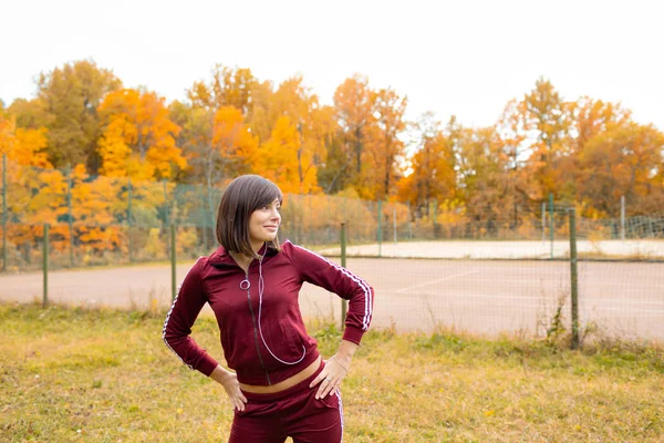 Porträt einer jungen Frau im Herbstwald. Brünette Frau im Herbstpark macht einen Lauf und wärmt sich auf. Sportlicher Lebensstil — Stockfoto