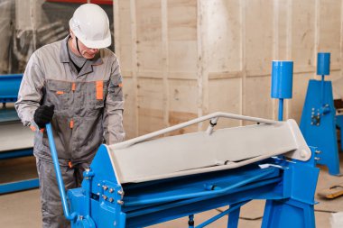 İşçiler depoda makine ayarlar. Havalandırma ve oluklar üretimi. Araç ve Sac bükme donatımı. Atölye üretimi.