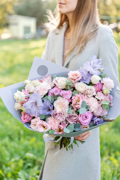 Бузковий і рожевий пастельний красивий весняний букет. Молода дівчина тримає квіткову композицію з різними квітами. Яскравий світанок або захід сонця — стокове фото