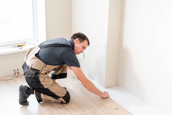 Arbeiter verlegen neue Holzlaminatböden auf einem warmen Folienboden. Infrarot-Fußbodenheizung unter Laminatboden — Stockfoto