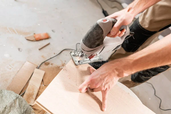 Hombre trabajador corta la placa laminada con una sierra electrostática. la instalación de nuevos pisos laminados de madera. concepto de reparación en casa . — Foto de Stock