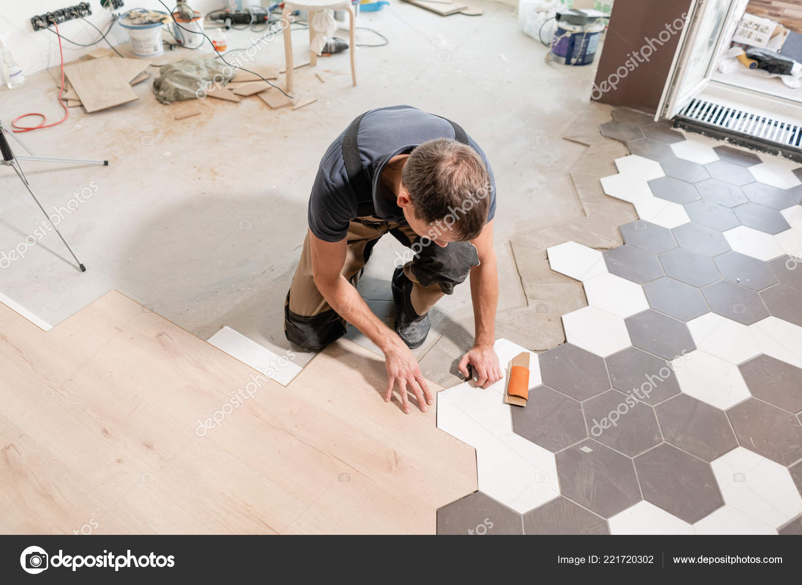 Trabajador masculino instalando nuevos pisos laminados de madera. La  combinación de paneles de madera de baldosas laminadas y cerámicas en forma  de panal. Renovación de cocina . — Foto de stock #221720302 © MalkovKosta, image size:1600x1167