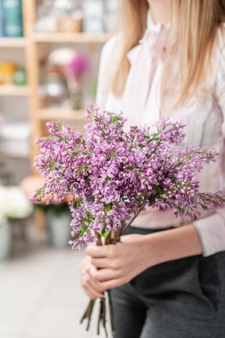 Güneşli bahar sabahı. Güzel bir demet leylak tutan genç mutlu kadın. Gülümsüyor kız için hediye.