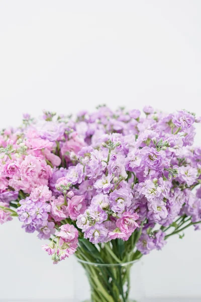 美丽的丁香花颜色紫罗兰, levkoy 或紫罗兰花束。春天的花朵在花瓶的木桌上。垂直照片 — 图库照片