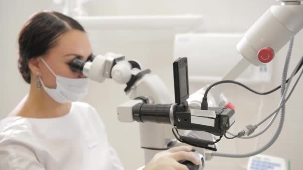 La doctora dentista usa un microscopio. Medicina, salud, concepto estomatológico. dentista realiza inspección y concluye. — Vídeo de stock