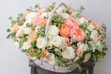 Hasır sepet ile gri duvarının yakınında ahşap masaya güzel çiçek karıştırın. Güzel bahçe çiçek düzenleme, profesyonel çiçekçi iş. Avrupa çiçek dükkanı