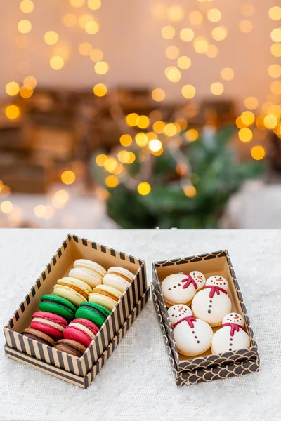 Verschiedene süße Makronen im Karton. Keks in Form eines Schneemanns. Frohe Weihnachten. Neujahrsstimmung. Lichter aus Girlanden — Stockfoto