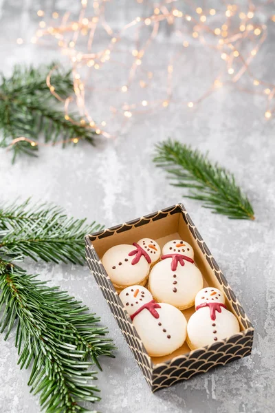 Verschiedene süße Makronen im Karton. Keks in Form eines Schneemanns. Tannenzweige auf grauem Hintergrund. Frohe Weihnachten. Neujahrsstimmung — Stockfoto