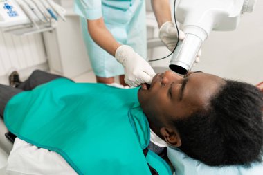 Kadın dişçi röntgen, diş hekimliği sandalyede yatan hasta makinasıyla. Genç Afro-Amerikan erkek kötü dişli. Tıp, sağlık, stomatology kavramı.