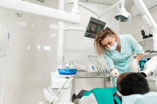 Žena zubař x ray stroji, trpělivý, ležící na židli v zubním lékařství. Mladý Američan Afričana muž s špatné zuby. Lékařství, zdravotnictví, stomatologie koncept. — Stock fotografie