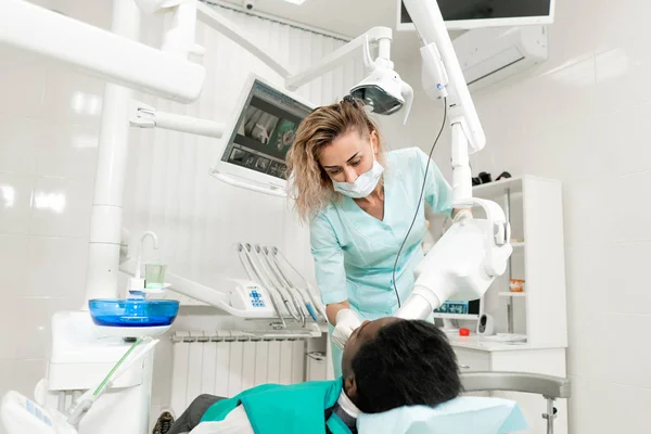 Žena zubař x ray stroji, trpělivý, ležící na židli v zubním lékařství. Mladý Američan Afričana muž s špatné zuby. Lékařství, zdravotnictví, stomatologie koncept. — Stock fotografie