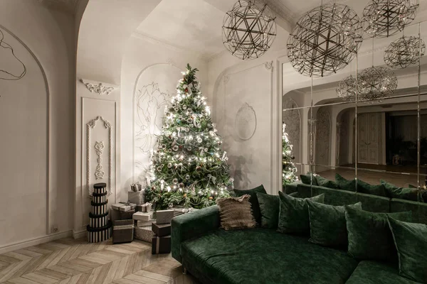 Garland light bulbs. Christmas evening. classic luxurious apartments with decorated christmas tree. Living hall large mirror, green sofa, high windows, columns and stucco.