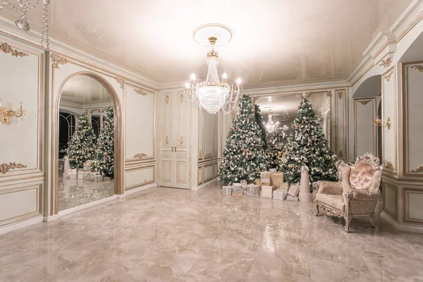 Christmas evening. classic luxurious apartments with decorated christmas tree. Living hall large mirror, chair, high windows, columns and stucco.