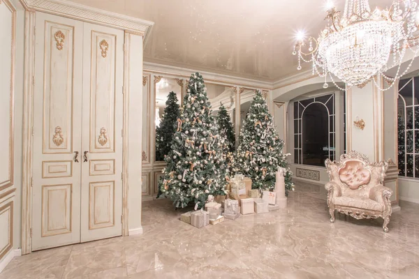 Vánoční večer. Klasické luxusní apartmány s nazdobený vánoční stromeček. Obývací hala velké zrcadlo, křeslo, vysokými okny, sloupy a štuk. — Stock fotografie