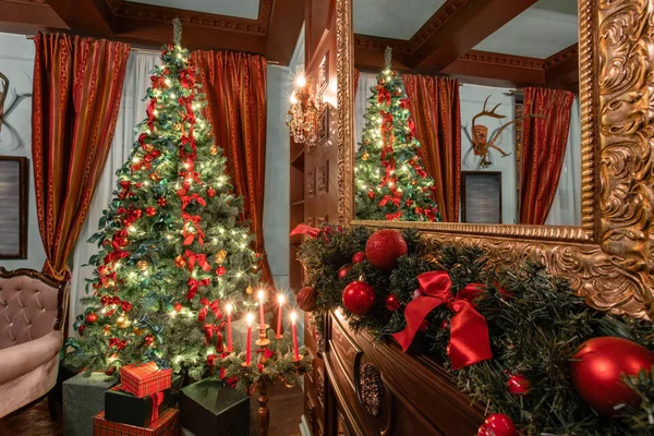 Kerst avond. Geschenken bij de kerstboom. Klassieke appartementen met een open haard. Kamer met planken van boeken — Stockfoto