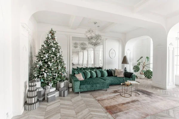 Πρωί Χριστουγέννων. Κλασικό πολυτελές διαμερίσματα με διακόσμηση χριστουγεννιάτικο δέντρο. Αίθουσα σαλόνι μεγάλο καθρέφτη, πράσινο καναπέ, ψηλά παράθυρα, κίονες και στόκο. — Φωτογραφία Αρχείου